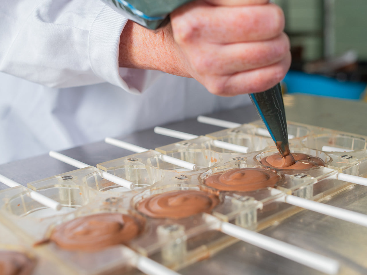 Image of a baker piping chocolate into lollypop moulds
