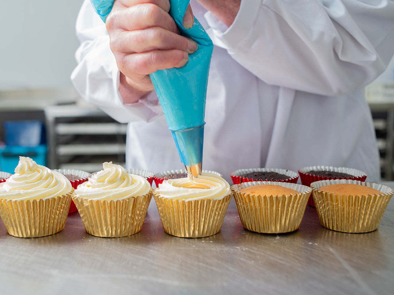 A baker piping icing onto cupcakes