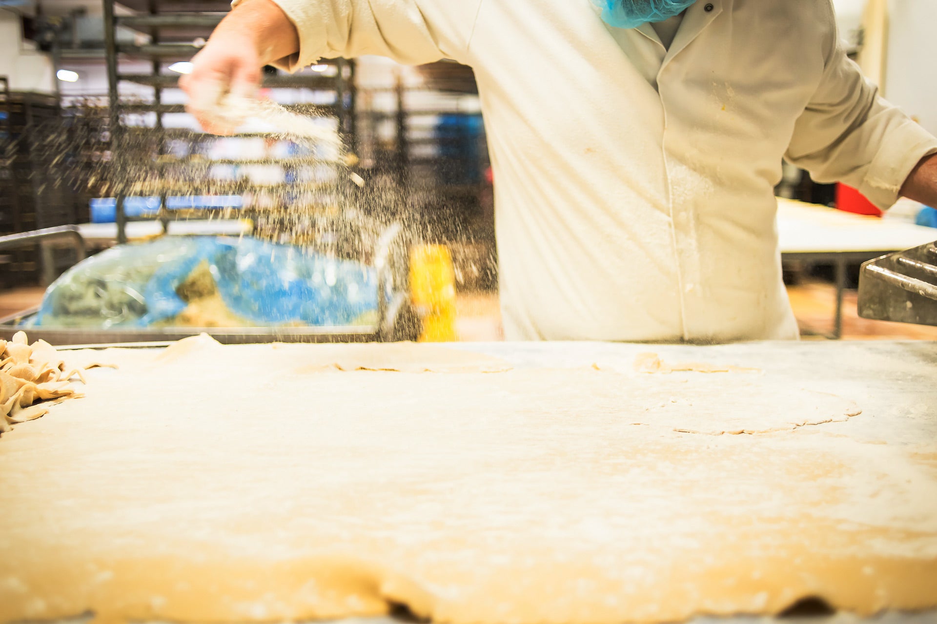 Baker sprinkling flour on dough