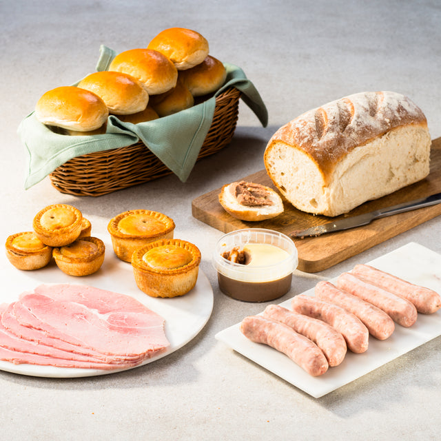 Savoury selection including a loaf of bread, rolls, sausages, pies and deli meats