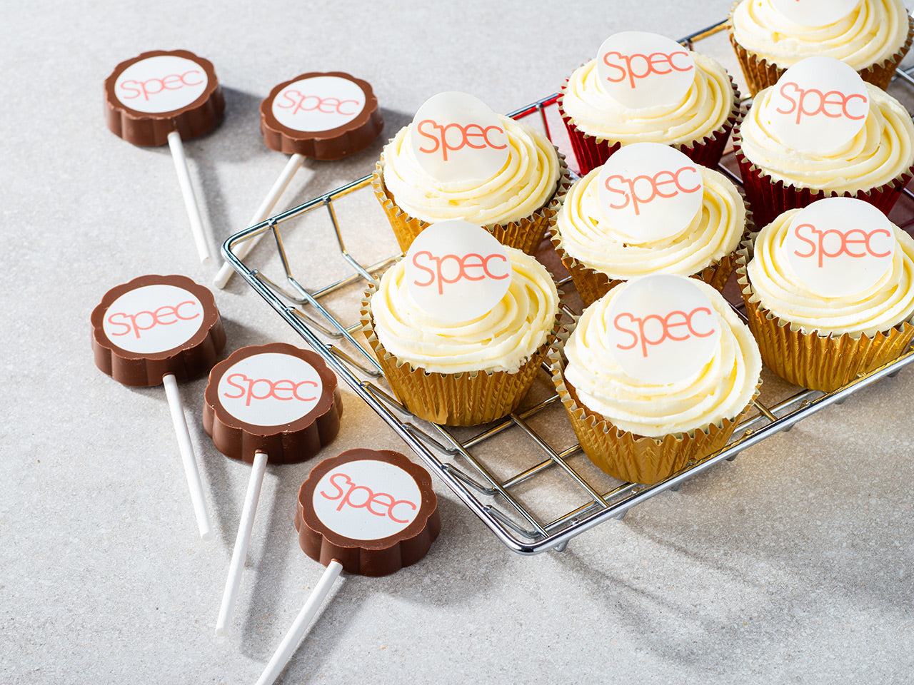 Selection of cupcakes and chocolate lollypops with brand names on top